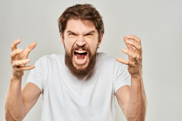 bearded man gesturing with his hands in a white t-shirt aggression light background