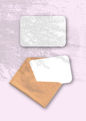 An envelope with two sheets of textured white paper on the pink background of the table. Mockup...