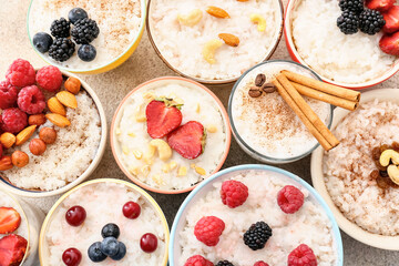 Bowls of tasty rice pudding with berries on light table