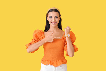 Young woman with wristwatch on color background