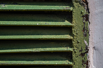 Rusty metal grilles, painted with paint and peeled off from old age, ventilation holes for air ingress in industrial facilities, an electric shield, an opening door
