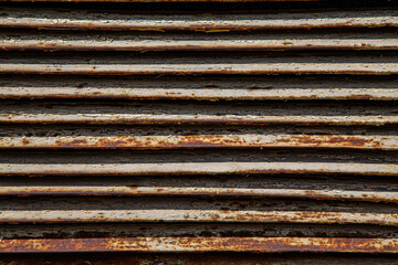 Rusty metal grilles, painted with paint and peeled off from old age, ventilation holes for air ingress in industrial facilities, an electric shield, an opening door