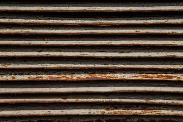 Rusty metal grilles, painted with paint and peeled off from old age, ventilation holes for air ingress in industrial facilities, an electric shield, an opening door