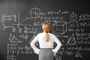 Mature maths teacher near blackboard in classroom