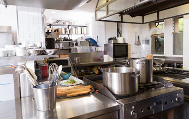 Typical working kitchen interior in restaurant with variety of equipment, utensils and foodstuffs