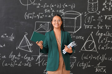 Asian female teacher near blackboard in classroom