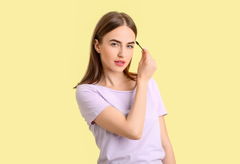 Young woman undergoing eyebrow correction procedure on color background