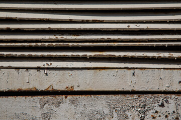 Rusty metal grilles, painted with paint and peeled off from old age, ventilation holes for air ingress in industrial facilities, an electric shield, an opening door