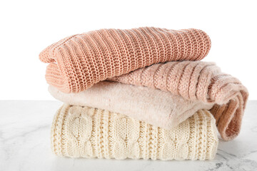 Stylish winter clothes on table against white background