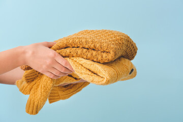 Female hands with warm clothes on color background