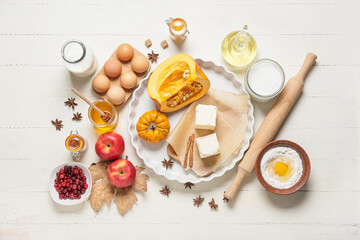 Ingredients for preparing pumpkin pie on white wooden background