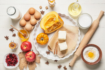 Ingredients for preparing pumpkin pie on white wooden background