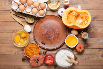 Ingredients for preparing pumpkin pie and plate on wooden background