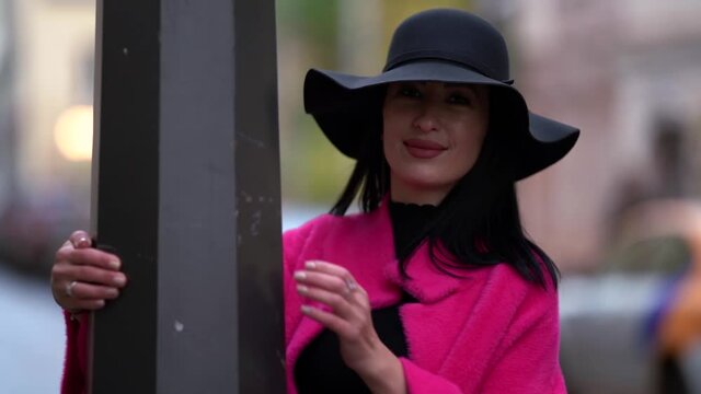 middle-aged woman is walking in downtown, dressed fashion pink coat and black felt hat