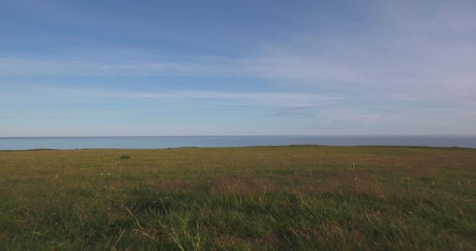Meadow on Top of Hill in The Summer Evening to The Baltic Sea, In South Sweden Sk&aring;ne &Ouml;sterlen K&aring;seberga Near Ales Stenar, Aerial Low From Close To Ground To Far From Sea Level