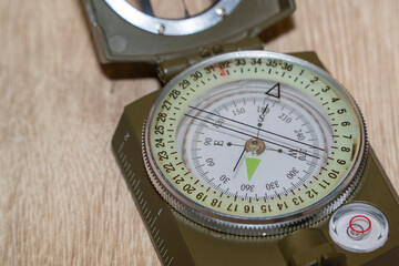 Close-up of a military compass on a wooden surface. Determining the direction of the compass.