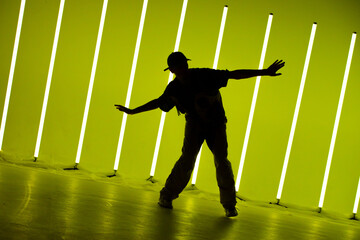 Cool young guy breakdancer dancing hip-hop in colorful background with neon lamps. Breakdancing...