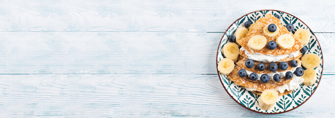 Christmas tree shaped sweet crepes with cream greek yogurt and blueberries on white wooden table. Web banner