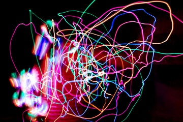 Multi color light painting photography, swirl and curve of blue, green and red light against a black background.