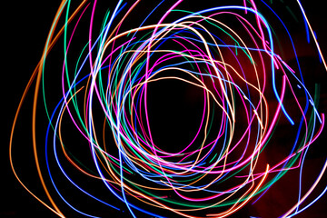 Multi color light painting photography, swirl and curve of blue, green and red light against a black background.