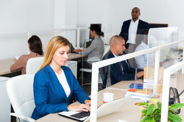 Portrait of businesswoman concentrated on work with laptop in coworking space with international team..