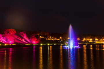Illuminated, colored fountain in the middle of the lake