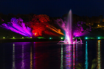 Illuminated, colored fountain in the middle of the lake