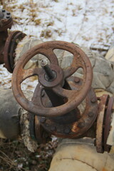 Old damaged and rusty iron oil pipe valve wheel. Metal, pipeline and mechanic concept. An old iron valve on a gas pipe. A valve to cover the pipe with a round handle