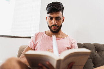 young latin american man reading on home