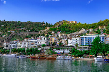 Turkey, Alanya - October 22, 2020: Peninsula with modern cottages and ancient Alanya Kalesi on hilltop. Parked yachts in Mediterranean Sea in Alanya Marina against the backdrop of a tourist cityscape