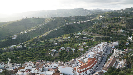 Nerja village architecture with white painted houses in a green hill landscape along the Costa del Sol in Spain.