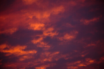 Stormy clouds and crimson sunset. Purple glow on the evening clouds. Sky patterns as background.