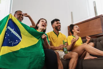 Fotobehang real latin american family watching football on television, celebrating goal of brazil © Brastock Images