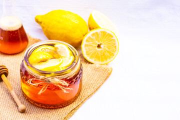 Honey in a glass jar with lemon on white background