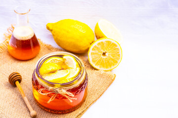 Honey in a glass jar with lemon on white background