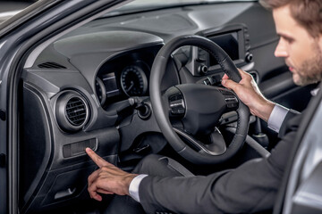 Young male holding steering wheel, pressing control buttons