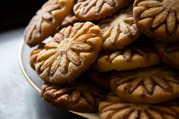 Shortbread biscuits close-up with powdered sugar and cocoa on a glass plate on a black blurred background