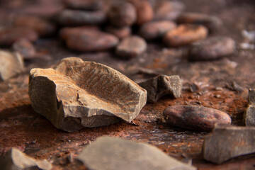 Cocoa mass with cocoa beans on a dark background close-up