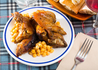 Delicious roasted pettitoes garnished with chickpeas on white dish ..
