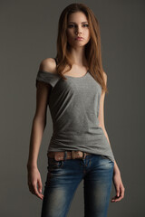 beautiful slender model in a gray t-shirt and jeans on a gray background