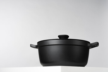 One new black cooking pot on white table