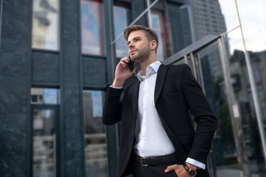 Young man in a black suit talking on the phone and looking involved
