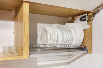 set of plates, cups on the shelf in the kitchen cabinet