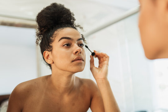 Beautiful latin american woman using mascara in bathroom