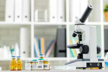 Vaccine bottles and microscope on table in a scientific lab