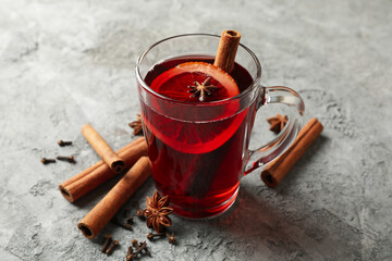 Glass of mulled wine and cinnamon on gray background