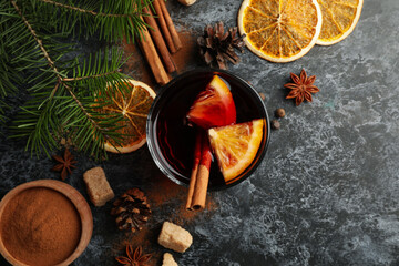 Glass of mulled wine and ingredients on black smokey background