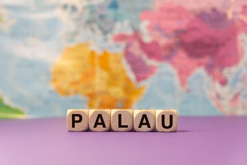 The word Palau written with wooden dices in front of a purple background and a geographic map
