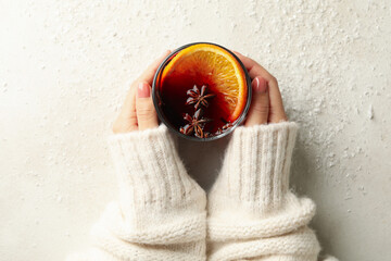 Female hands hold glass of mulled wine on white background with snow