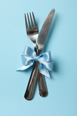 Cutlery with blue bow on blue background
